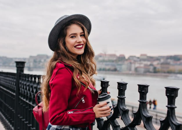 Adult woman holding a takeaway cup beside a waterfront railing