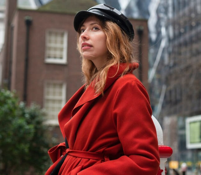 Adult woman in a red coat standing in an urban setting